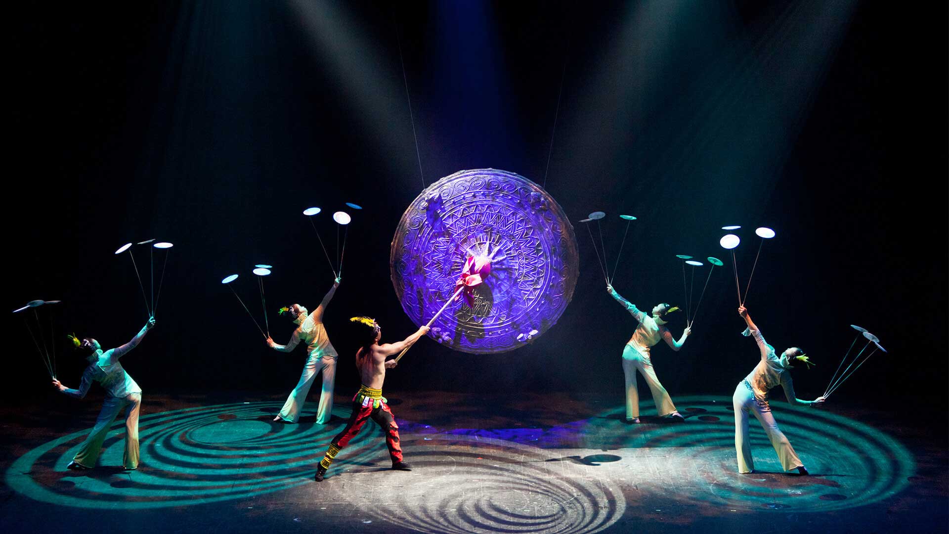 The Golden Dragon Acrobats perform feats of athleticism and artistry on a stage centered by a giant gong.